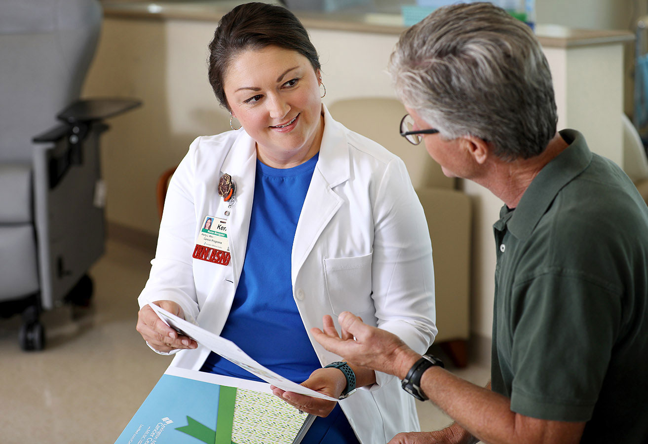 A smiling oncologist sharing a pamphlet with a patient.