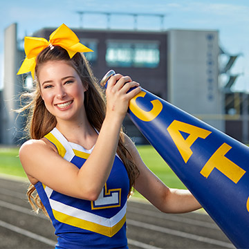 Madison Kutyla in her cheerleading uniform holding a megaphone.